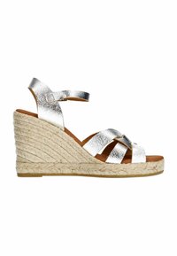 Zilverkleurige metallic wedge sandalen met een kruisriemontwerp, geweven jute zool en een bruine voetbed. Verstelbare enkelband voor pasvorm.