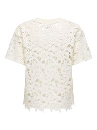Blouse blanche à manches courtes en dentelle avec motifs floraux et ourlet festonné, tissu semi-transparent révélant une couche intérieure.