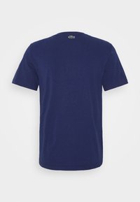 Navy blue cotton t-shirt with short sleeves, round neck, and small green logo at the back. Smooth texture, standard fit, minimal design.