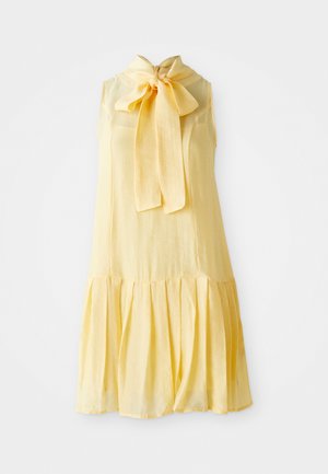 Vestito senza maniche di un delicato giallo pallido, con collo alto e un grande fiocco, caratterizzato da un orlo arricciato per una silhouette fluente.