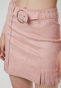 Rosa Wildleder-Minirock mit einem taillierten Bund und goldfarbenen Beschlägen, Nietenakzenten und Fransendetails am Saum.