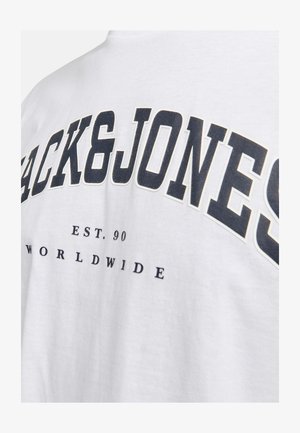 Biela bavlnená tričko s veľkým čiernym textom "BACK&JONES", s menším potlačou "EST. 90" a "WORLDWIDE" pod ním.