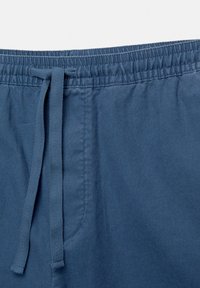 Shorts en coton bleu avec une taille élastique et un cordon de serrage. Comprend une poche latérale et une finition lisse et texturée.