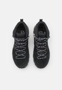 Scarpe da trekking nere con una tomaia in suede testurizzato e mesh, occhielli rinforzati e lacci riflettenti, dotate di una suola in gomma resistente.