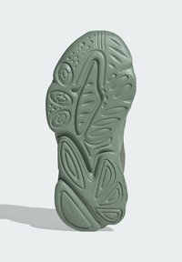 Green rubber sneaker sole features varying textured patterns, grooves, and raised accents for grip and cushioning.