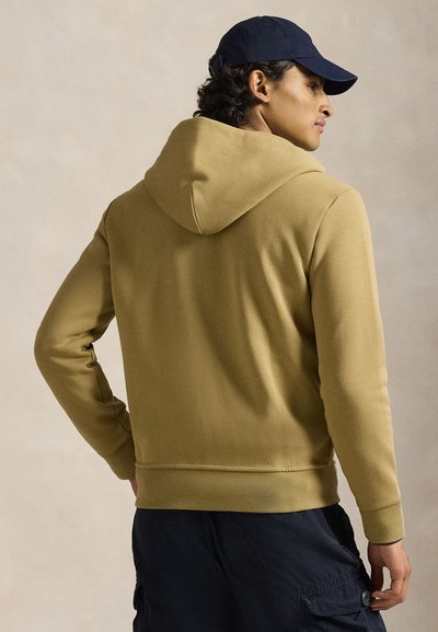 Χακί φούτερ με κουκούλα, με λείο ύφασμα, ριμπ μανσέτες και τελείωμα. Εφαρμοστό σχέδιο με διακριτική λεπτομέρεια ραφής, συνοδευόμενο από σκούφο σε ναυτικό μπλε χρώμα.