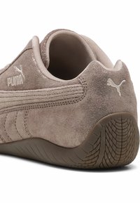 Sneaker Puma in camoscio beige con focus sul tallone e dettagli laterali, mostrando la suola strutturata e il logo Puma ricamato.