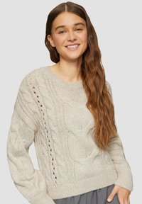 Helles beiges, kabelgezeichnetes Sweatshirt mit strukturiertem Muster, gerippten Ärmelbündchen und lockerer Passform. Verfügt über offene Strickakzente an den Seiten.