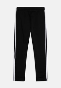 Pantalones jogger negros con rayas laterales blancas, cintura elástica, piernas ajustadas y textura suave. Diseñados para comodidad y uso casual.