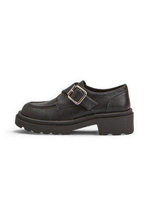 Mocassino in pelle nera con suola spessa e grande cinturino con fibbia argento sulla parte superiore, mostrato di profilo su sfondo bianco.