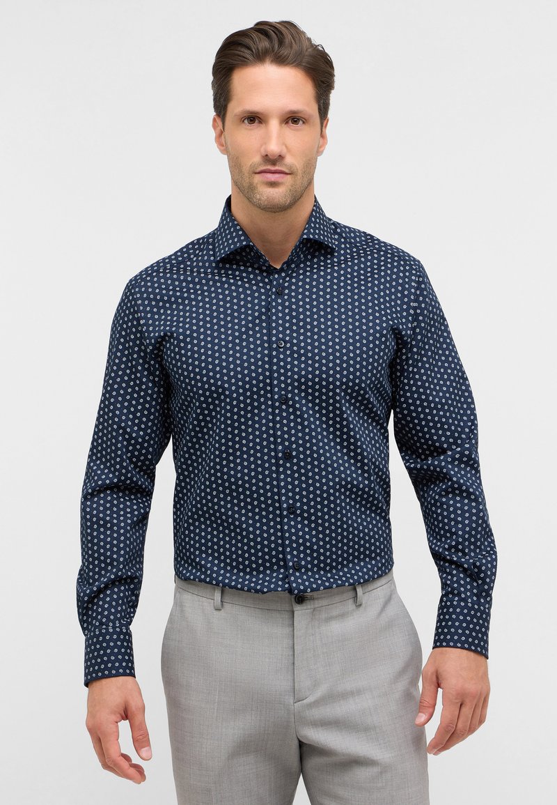 Camicia blu navy con un piccolo motivo circolare bianco. Maniche lunghe con polsini abbottonati, tessuto leggero e vestibilità sagomata.