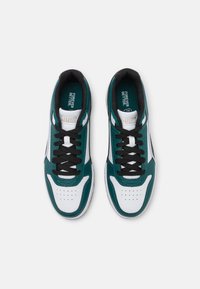 Baskets vertes et blanches avec des lacets noirs, dotées d'une tige en cuir lisse, d'un bout perforé et d'un logo sur la languette et la semelle intérieure.