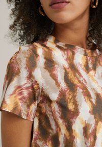 Short-sleeve top in a tie-dye pattern featuring shades of brown, pink, and cream, with a round neckline and soft, smooth texture.