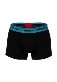Schwarze Herrenboxershorts mit einem breiten, türkisfarbenen Bund, der das "HUGO"-Logo in Schwarz trägt, und einem roten Etikett mit "HUGO" in der Mitte auf der Rückseite.
