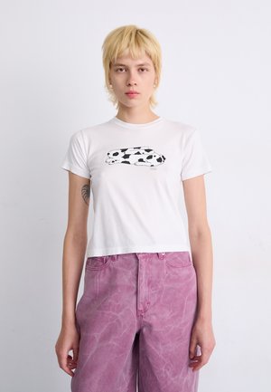 Hvid crop t-shirt med et sort-hvidt kaninmotiv. Kombineret med lyserøde denimbukser, der har et falmet og struktureret udseende.