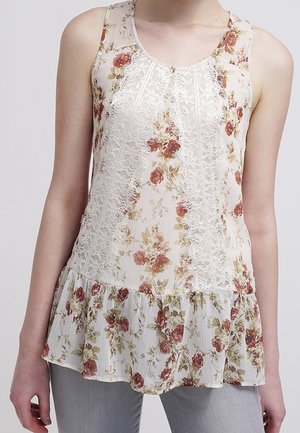 Kwiatowy top bez rękawów z koronkowymi zdobieniami, z marszczonym dołem typu peplum, w delikatnym kremowym kolorze i pastelowych kwiatowych wzorach. Lekka, teksturowana tkanina.