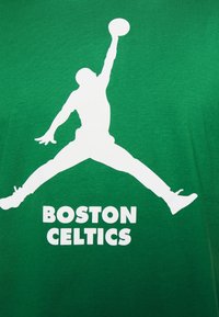 Silhuetti koripalloilijasta, joka hyppää pallo yllään valkoisena vihreällä taustalla, ja rohkealla tekstillä "BOSTON CELTICS" alapuolella.