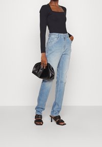 Svart långärmad bodysuit, ljusblå högmidjade jeans, svarta plisserade klacksandaler och en liten svart clutch. Enkel design, åtsittande form.