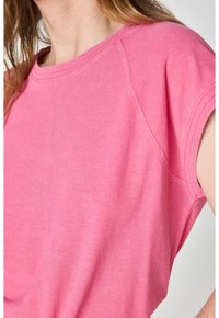 T-shirt a maniche corte, con scollo rotondo, in un vivace tessuto misto cotone di colore rosa. Presenta maniche raglan e una finitura liscia e strutturata.