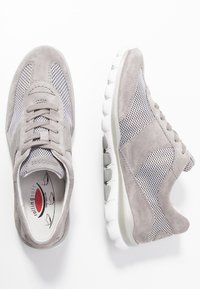 Grå sportskor med överdel i mocka och mesh, texturerade sidopaneler, snörning och gummisulor med böjda spår för grepp.