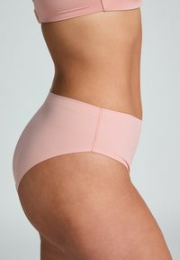 Bikini bottom rosa chiaro con una texture liscia, a vita media, e cuciture minime, che offre un aspetto senza cuciture lungo i lati e sul retro.