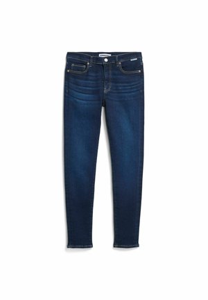 Donkere blauw skinny jeans met voor- en achterzakken, riemlussen, knoopsluiting en subtiele vervaging op de dijen, plat gelegd op een witte achtergrond.