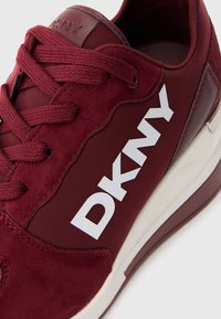 Burgundske tenisice sa kombinacijom antilopa i tkanine, bijelim DKNY logom, teksturiranim vezicama i kontrastnom off-white potplatom.