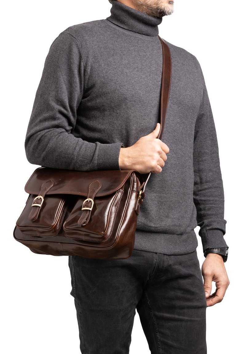 Borsa a tracolla in pelle marrone con due tasche frontali, decorazioni in metallo dorato e una tracolla regolabile. Texture liscia e forma rettangolare.