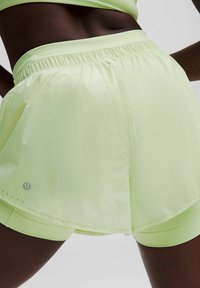 Hellgrüne Sportshorts mit einem elastischen Bund, einem geschichteten Design und kleinen Lochmusterungen in der Nähe des Logos auf der linken Seite.