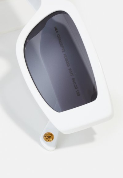 Weiße übergroße Sonnenbrille mit dunkelgrauen Gläsern. Sie hat ein geometrisches Design, eine glatte Textur und ein goldfarbenes Sonnenemblem-Detail an den Bügeln.