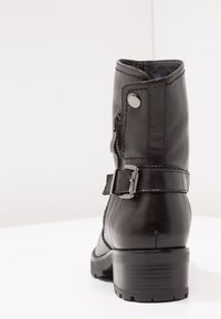Svarta läderankelstövlar med dragkedja, spänne, texturerad yta och låg klack med en robust sula.