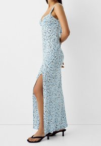 Modré květinové maxi šaty s těsným korzetem, nastavitelnými ramínky a rozparkem až k stehně. Vyrobené z lehkého materiálu s hladkým povrchem.