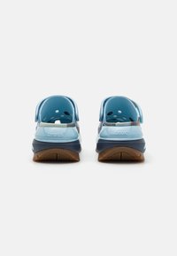 Blå gummiklär med en mörkblå sula, utrustade med ventilationshål, justerbara hälremmar och "crocs"-logotyp på baksidan.
