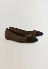 Braune Wildleder-Ballerinas mit einer schwarzen Wildlederkappe und einer dekorativen Schleife vorne. Das Design ist flach mit einem leichten Absatz.