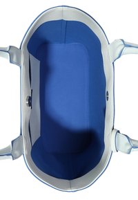 Miękka biała torba z niebieskim wnętrzem. Owalny kształt, teksturowany materiał zewnętrzny, kontrastowe wykończenie. Jedna wewnętrzna kieszeń, zapinana na guzik.