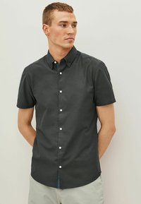 Camisa de botones de manga corta en gris oscuro, con cuello tipo solapa, botones y un cuello interior con un patrón. Textura suave, corte relajado.