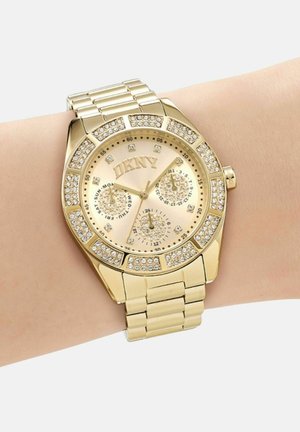 Orologio da polso DKNY in oro con dettagli in cristallo, dotato di tre quadranti secondari per giorno, data e orario 24 ore, su un bracciale a maglie.