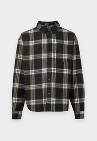 Μαύρο πουκάμισο με κουμπιά και μακριά μανίκια, με σχέδιο καρό σε μπεζ, λευκό και γκρι, και μία τσέπη στο στήθος αριστερά.