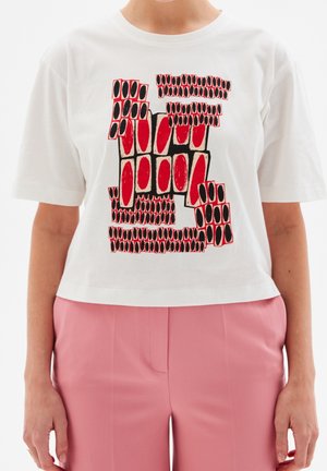 Hvid kortærmet crop-top med fedt grafisk design i rødt og sort med forskellige former og mønstre. Kombineret med pink bukser.