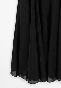 Sort nederdel lavet af letvægts, krøllet stof. Har et flydende design med en blød tekstur og en kant, der hænger elegant.