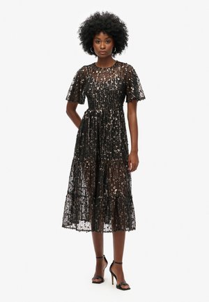 Abito midi nero con paillettes, maniche a sbuffo corte, scollatura rotonda e gonna a balze. Presenta una sovrapposizione trasparente e una fodera morbida.