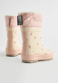 Bottes de pluie en caoutchouc avec un revers matelassé rose clair, un corps crème avec des illustrations de fruits, et une semelle rose texturée avec des rainures pour une traction optimale.
