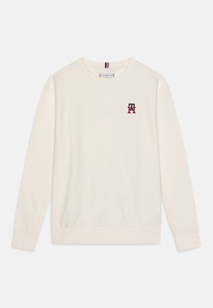 Flødefarvet langærmet sweatshirt med rund hals, lille rød og marineblå "TH" logo på venstre bryst samt ribstrikkede manchetter og kant.