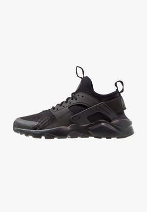 Czarny sportowy sneaker z siateczkową cholewką, grubą podeszwą, wiązany z przodu, z pętlami na pięcie i języku, pokazany od zewnętrznej strony.