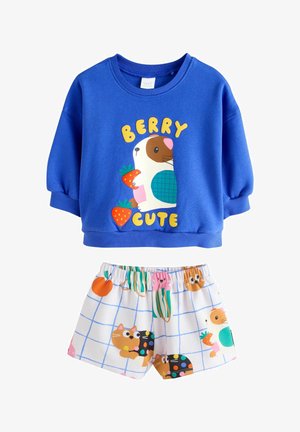 Blå sweatshirt med teksten "Berry Cute" og marsvin, der holder jordbær, kombineret med hvide shorts med farverige katte- og frugtmønstre.