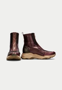 Scarpe alte con una tomaia in tessuto bordeaux lucido e dettagli marroni testurizzati. Presentano una cerniera frontale e una suola beige spessa.