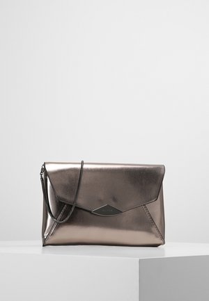 Skinnende bronze metallic kuverttaske med klaplukning og en tynd kæde som håndtag, vist på en hvid piedestal mod en ensfarvet baggrund.