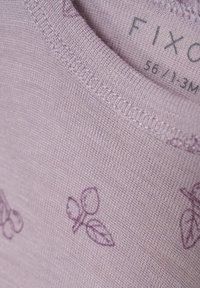 Ljust lila bomullsskjorta med korta ärmar, med ett diskret mönster av blad och bär i mörkare lila. Ribbad halsringning. Storleksmärke synligt.