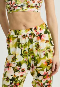 Kvetinový crop top a nohavicový set s farebným vzorom v zelených, ružových a bielych kvetoch. Mäkká tkanina s elastickým pásom a logom značky.
