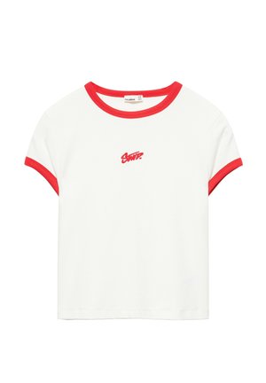 T-shirt blanc à manches courtes avec bordure rouge sur les manches et le col, avec un petit texte rouge brodé centré sur la poitrine.